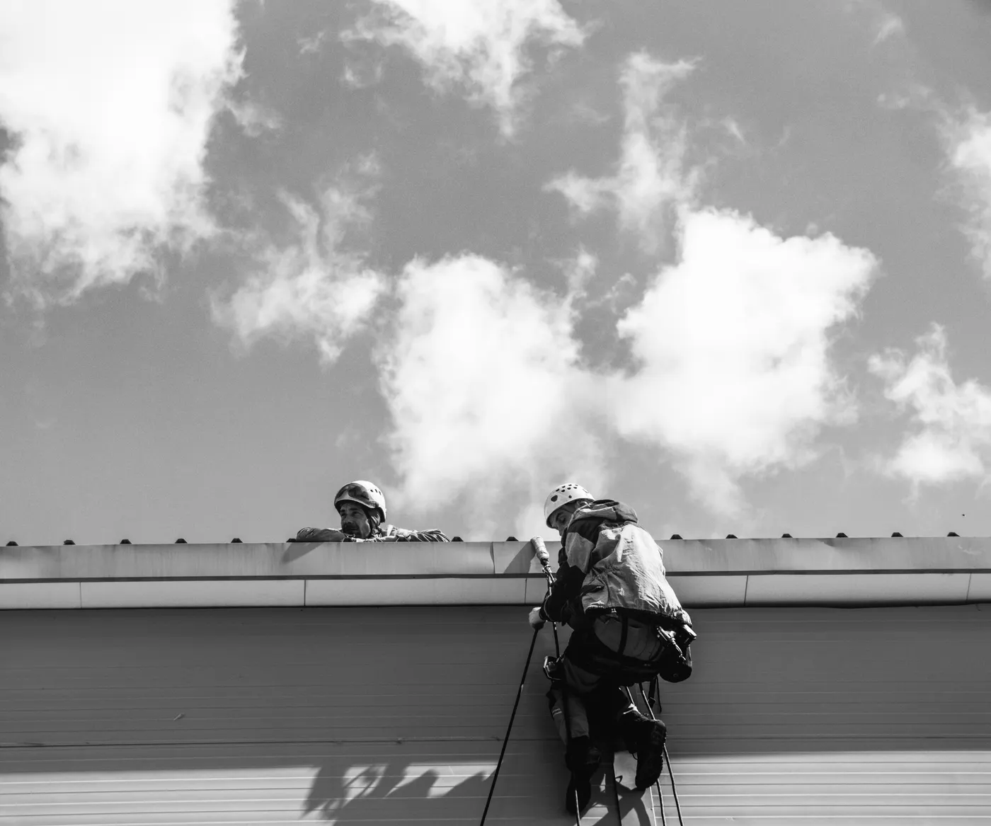 Técnicos com corda e ponto de ancoragem em cobertura industrial