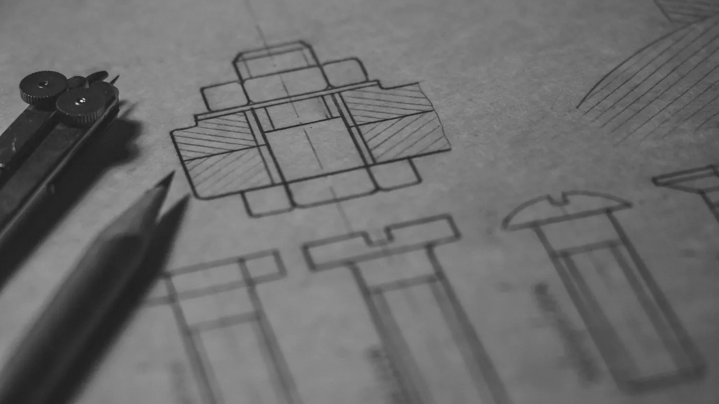 Desenho técnico mecânico com lápis e compasso sobre prancheta